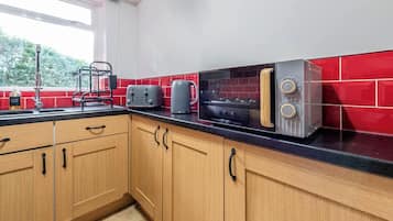 A kitchen with wooden cabinets, a black countertop, a toaster, a kettle, and a stove.