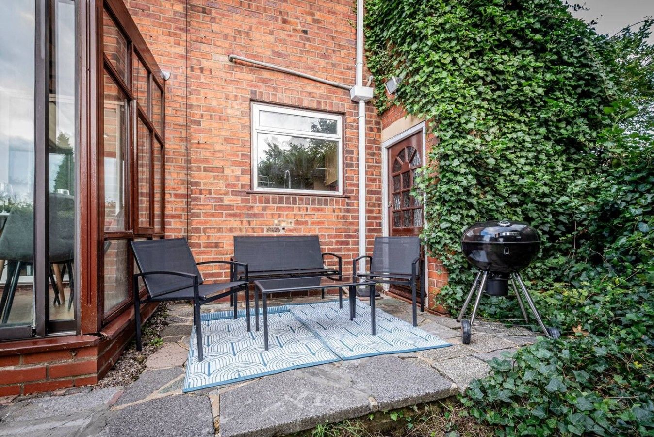 A brick building with a glass door, a window, and a patio with outdoor furniture.