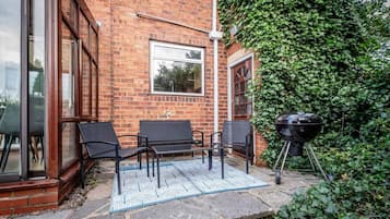 A brick building with a glass door, a window, and a patio with outdoor furniture.