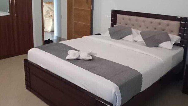A bedroom with a bed, a ceiling fan, a wardrobe, and a door leading to another room. - VENKAT INN (Bengaluru)