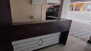 A reception desk with a dark wooden top and a white lower section. - VENKAT INN (Bengaluru)
