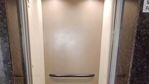 A narrow elevator with a metal handrail and a tiled floor. - VENKAT INN (Bengaluru)