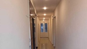 A long, narrow hallway with a tiled floor and white walls. - VENKAT INN (Bengaluru)