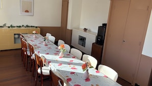 A dining area with a long table, chairs, and a cabinet with kitchen appliances. - Central Hotel (Saint-Priest)