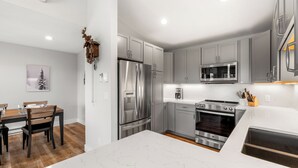Une cuisine moderne avec des meubles gris, des appareils en acier inoxydable et un plan de travail en marbre blanc.