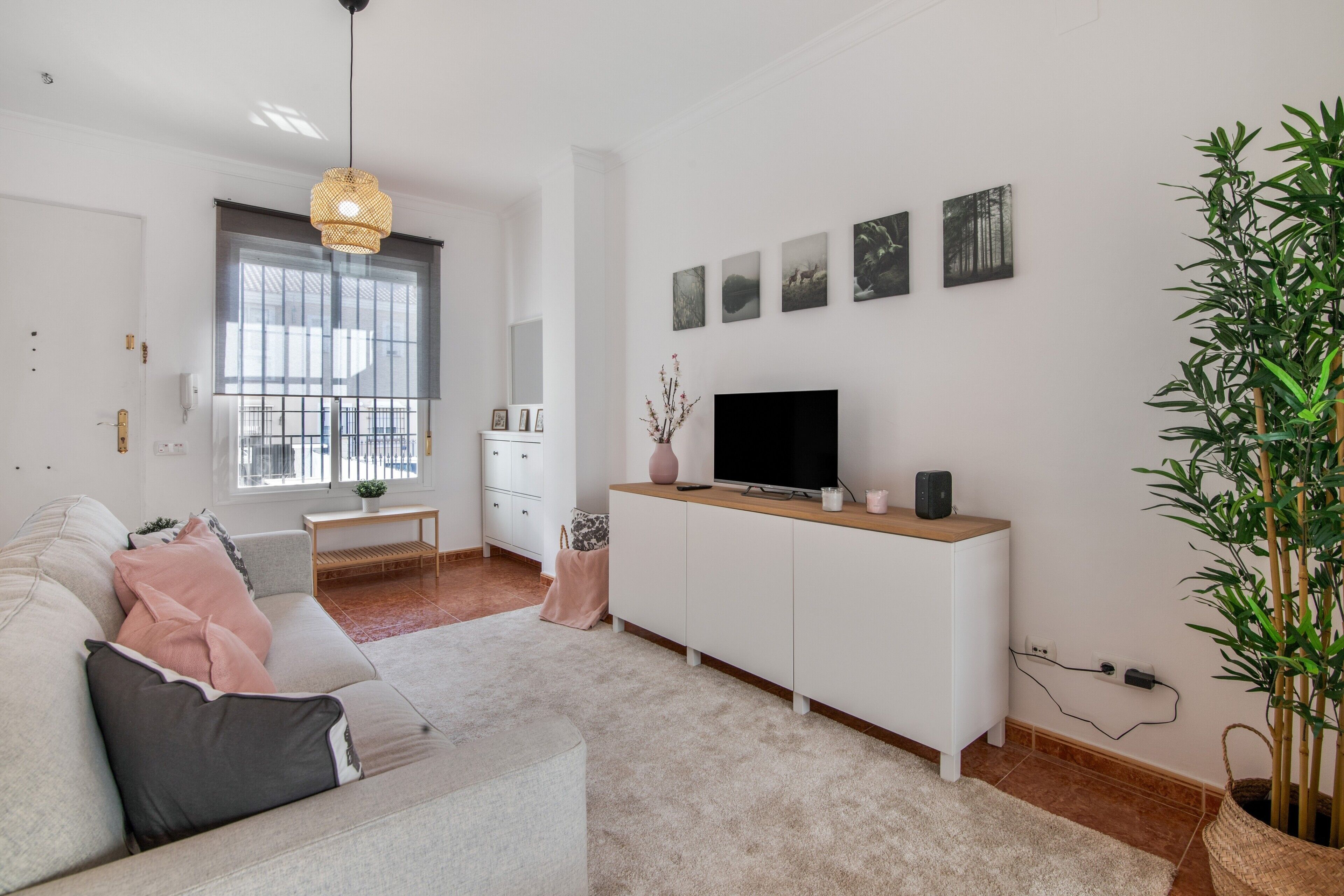 Een moderne woonkamer met een bank, televisie en kunstwerk aan de muur.
