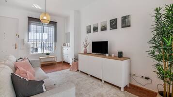 Een moderne woonkamer met een bank, televisie en kunstwerk aan de muur.