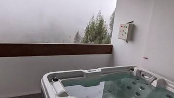A hot tub on a balcony with a wooden floor and a small table.