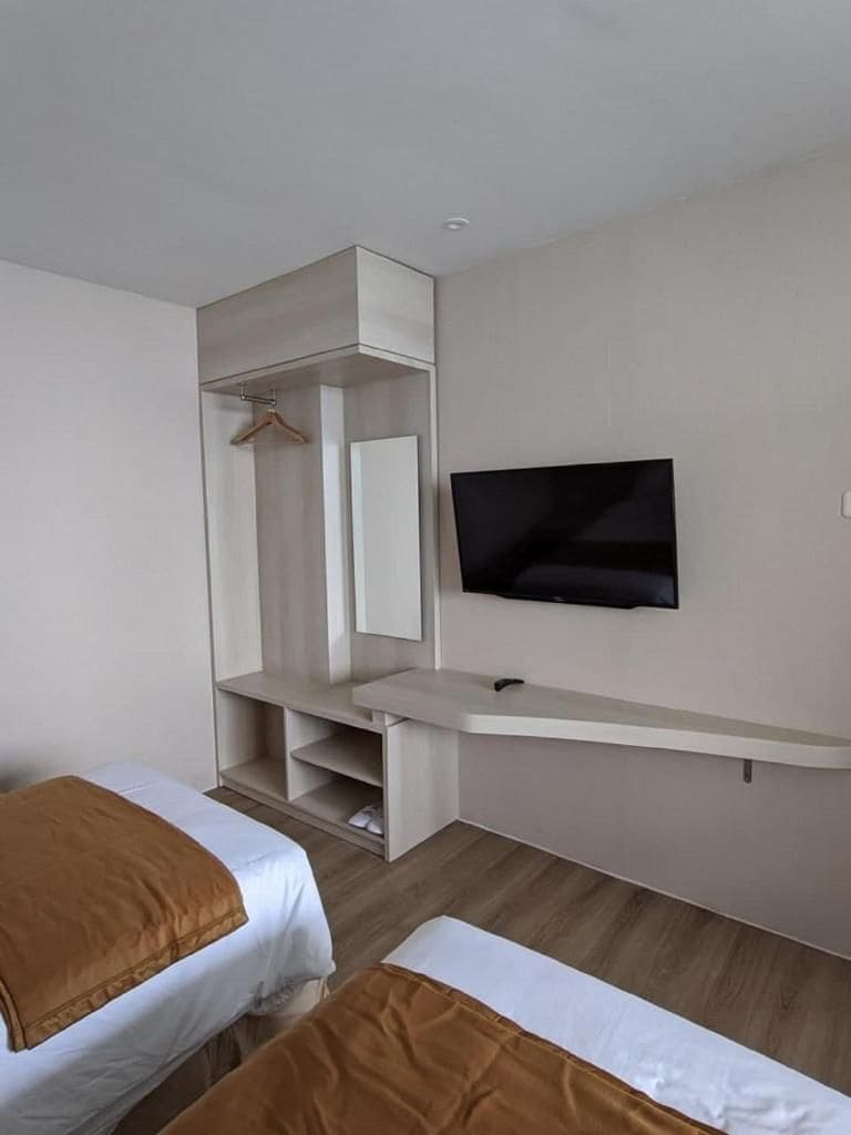 A hotel room with a bed, a TV mounted on the wall, and a built-in wardrobe.