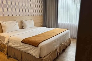 A neatly made bed with a headboard, a brown throw blanket, and a window with curtains. - Lereng Bromo Hotel (Tosari)