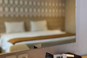 A hotel room with a bed, a bedside table, and a mirror reflecting the room. - Lereng Bromo Hotel (Tosari)
