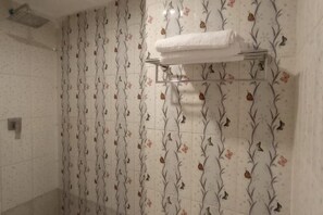 Une salle de bain avec des carreaux décorés de motifs floraux, un porte-serviettes et une pomme de douche.