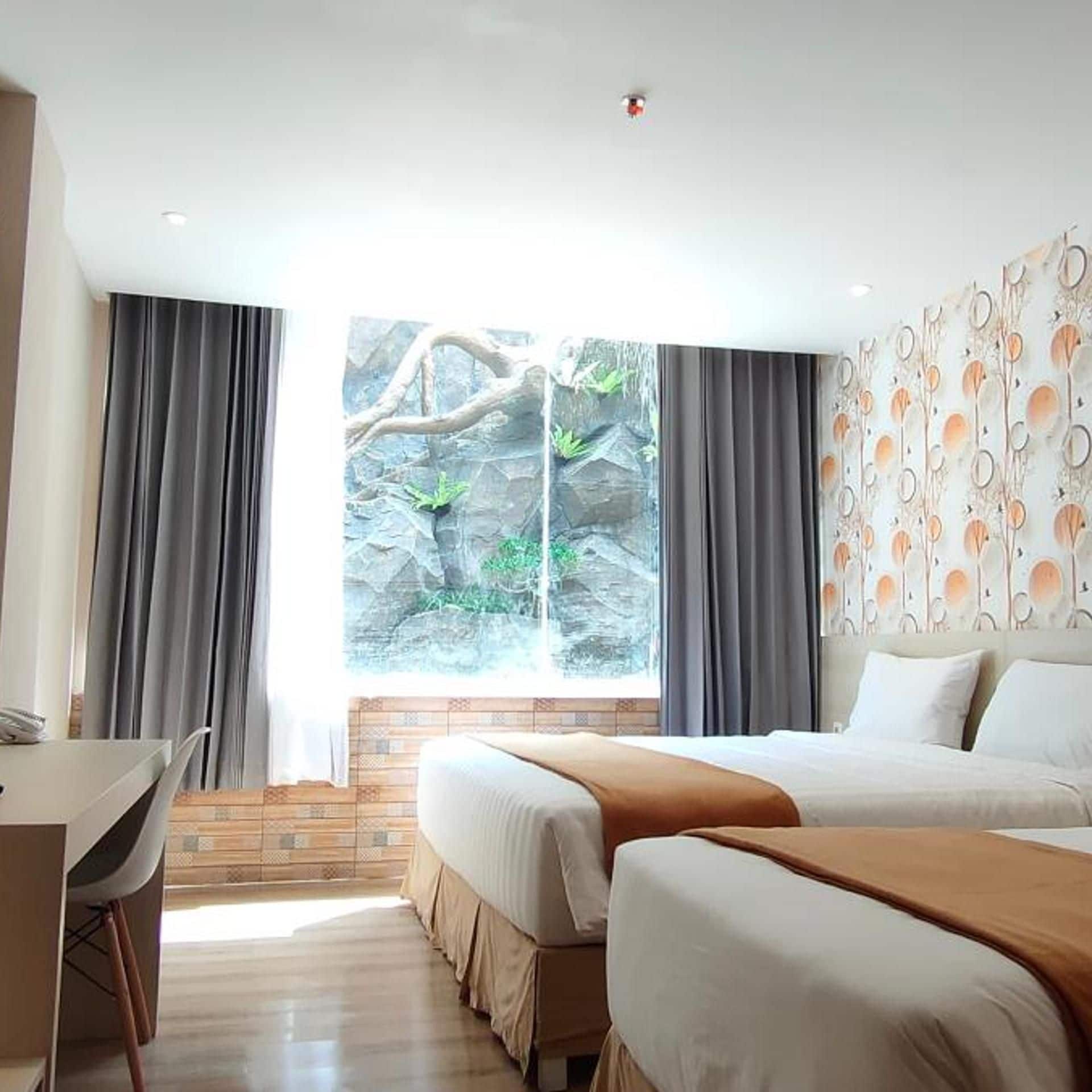 A hotel room with a bed, a desk, and a large window with curtains.