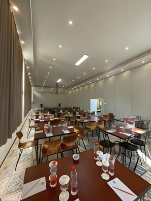 A conference room with multiple tables and chairs, equipped with nameplates, water bottles, and glasses. - Lereng Bromo Hotel (Tosari)