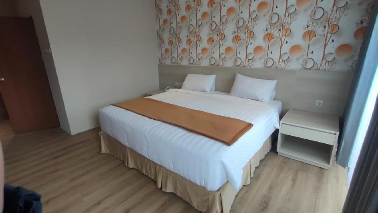 A hotel room with a bed, bedside tables, and a patterned wall.