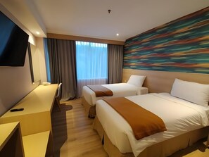 Quarto de hotel com duas camas, uma escrivaninha, televisão de tela plana e uma grande pintura abstrata na parede.