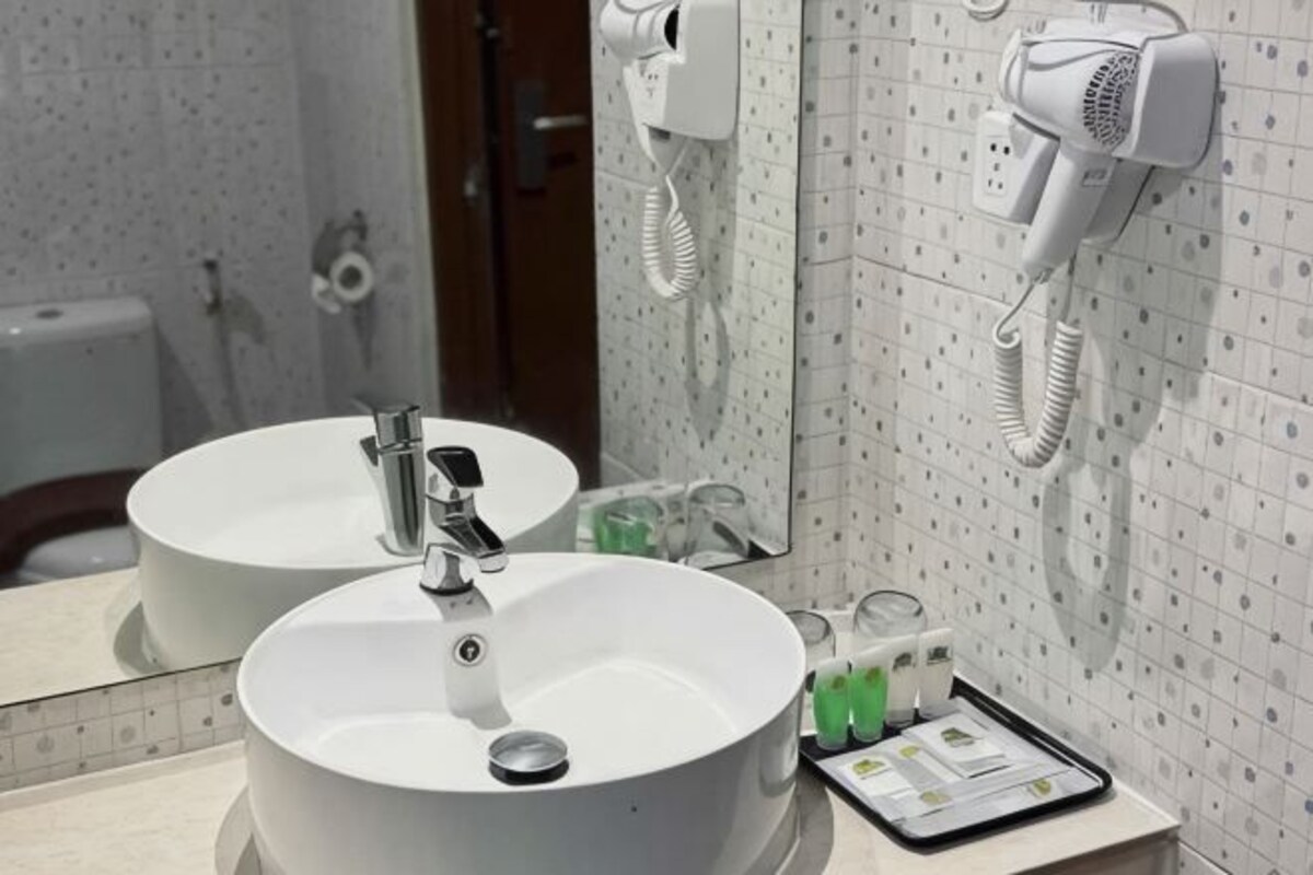 Un baño con dos lavamanos, un secador de pelo y un espejo.