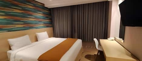 Une chambre d’hôtel avec un lit, un bureau, une chaise, une télévision et un tableau au mur.