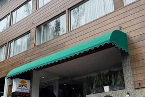 A hotel entrance with a green awning, large windows, and a visible signboard. - Lereng Bromo Hotel (Tosari)