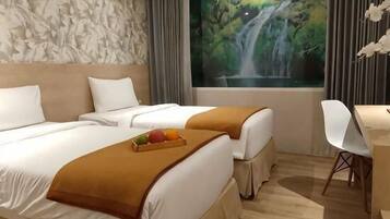 Een hotelkamer met twee bedden, een bureau en een groot raam met uitzicht op een waterval.