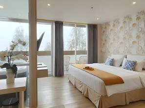 Quarto de hotel moderno com uma cama grande, uma escrivaninha e vista para árvores pela janela.