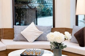 A sofa with cushions, a chessboard, and a vase with flowers. - Adalia Villa With ValeyView - O'TEL (Dalat)