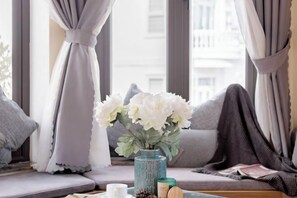 Ein Fensterplatz mit Blumen, einem Kissen und einer Zeitschrift.
