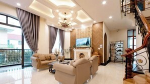 A spacious living room with a sofa set, a fireplace, and a large TV. - Adalia Villa With ValeyView - O'TEL (Dalat)