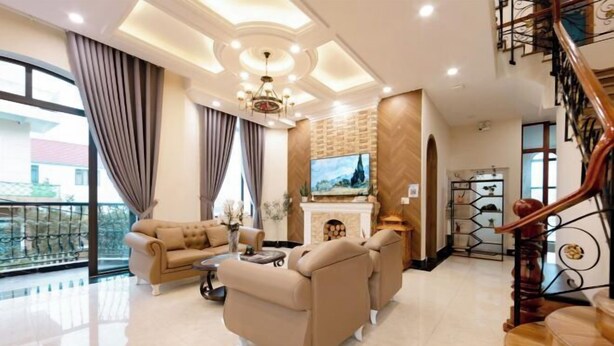 A spacious living room with a sofa set, a fireplace, and a large TV. - Adalia Villa With ValeyView - O'TEL (Dalat)