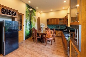 Une cuisine moderne avec des meubles en bois, un réfrigérateur noir et un coin repas comprenant des chaises et une table en bois.