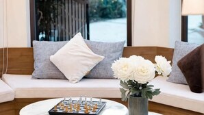 A sofa with cushions, a chessboard, and a vase with flowers. - Adalia Villa With ValeyView - O'TEL (Dalat)
