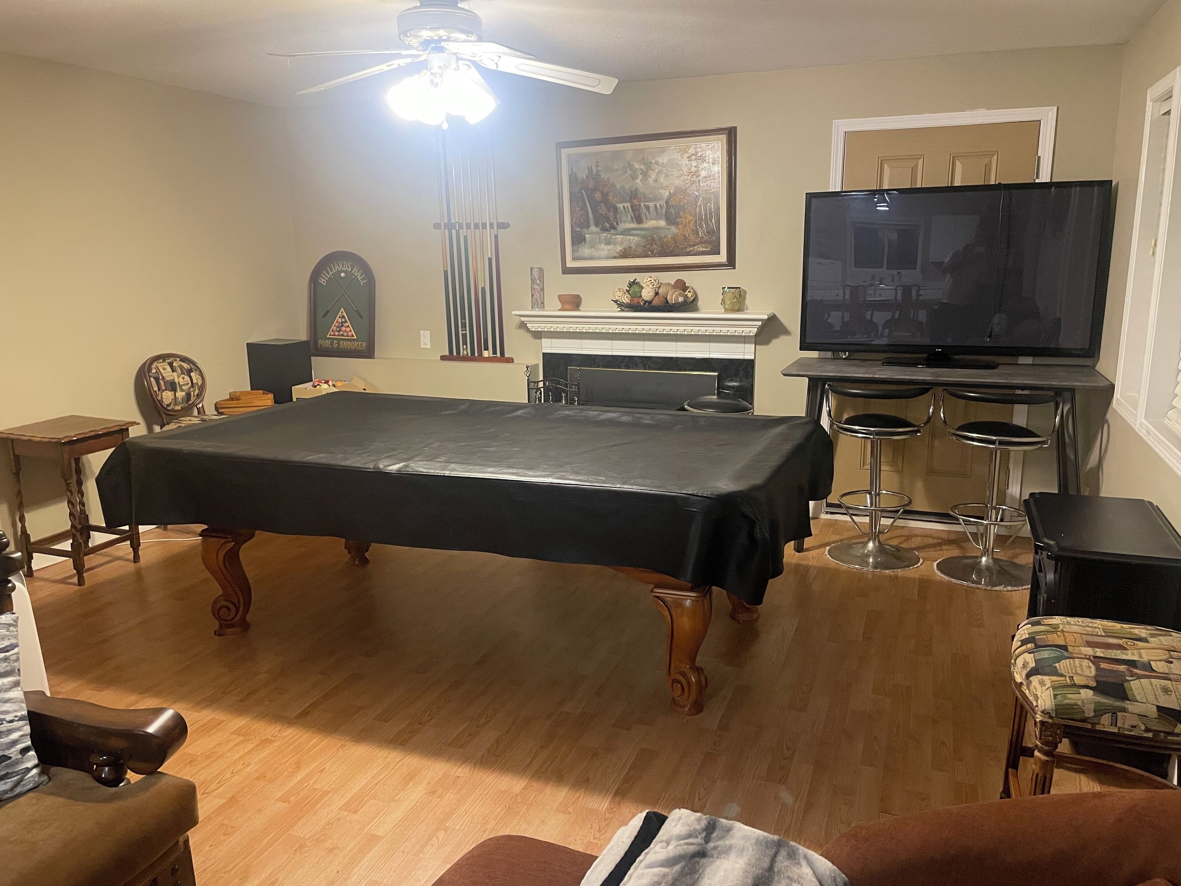 A living room with a pool table, a television, and a fireplace.