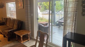 A cozy living room with a sofa, a wooden table, and a chair. There is a sliding glass door leading to an outdoor patio area. - Beautiful 3-bedroom apartment in Lindell Beach (Lindell Beach)