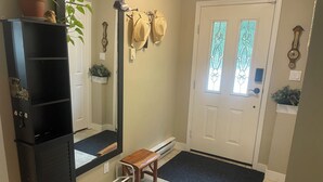 A hallway with a black cabinet, a wooden bench, a door with a glass panel, and a black mat at the entrance. - Beautiful 3-bedroom apartment in Lindell Beach (Lindell Beach)