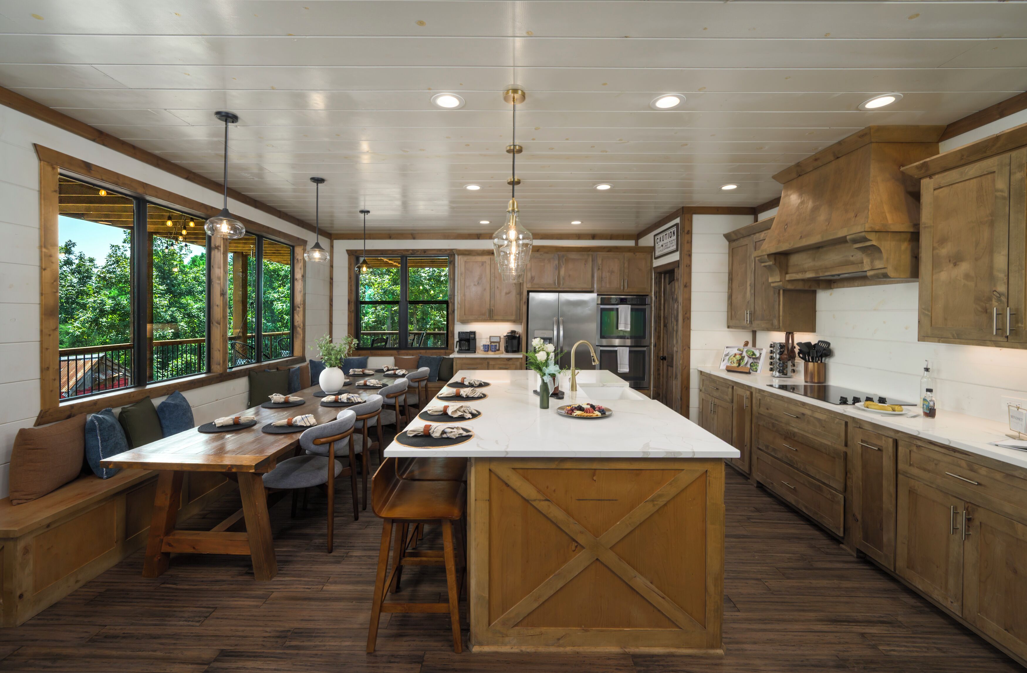 Une cuisine spacieuse dotée d’un grand îlot central, de meubles de rangement en bois et d’un coin repas avec une banquette et des chaises.