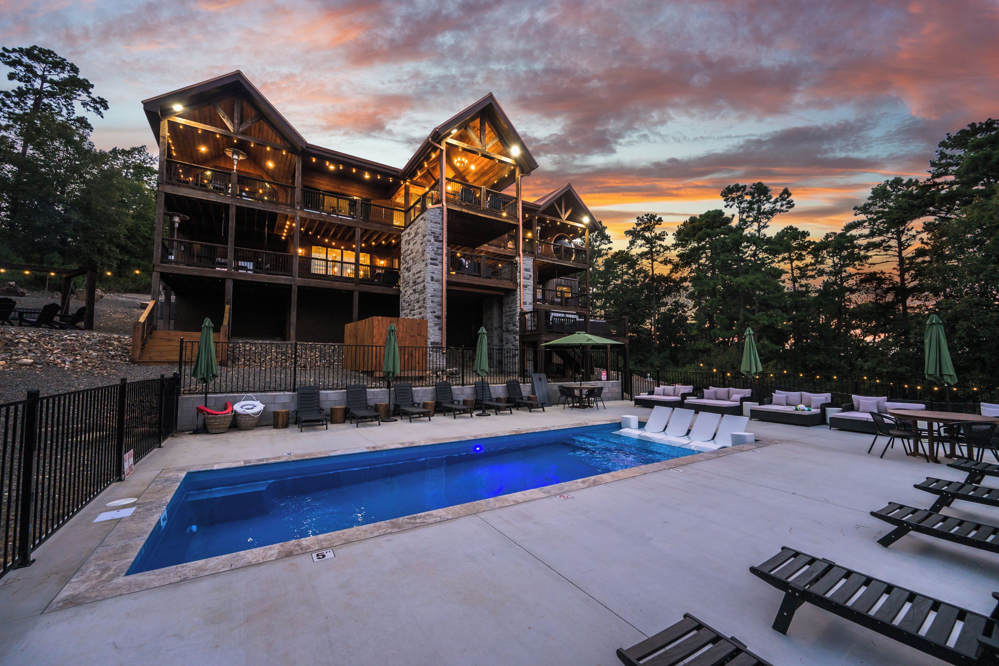 Un chalet à deux étages doté d’une piscine et d’un espace extérieur aménagé pour s’asseoir.