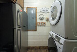 Una lavandería con lavadora, secadora y una puerta que indica 'Laundry Room'.