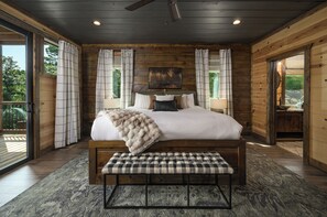 Ein Schlafzimmer mit einem großen Bett, einer Sitzbank und Blick ins Freie.