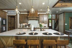 A spacious kitchen with a large island, wooden cabinets, and pendant lighting.