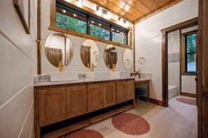 A bathroom with wooden cabinets, a double sink vanity, and a large mirror with three smaller mirrors above it.