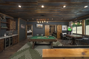 A cozy indoor space with a pool table, bar area, and a billiards table.