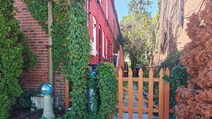 Un quartier résidentiel avec un immeuble en briques, une porte en bois et un chemin piétonnier en béton.