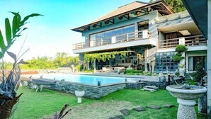 Une maison moderne à deux étages dotée d’une piscine, d’un chemin en pierre et d’un jardin aménagé.