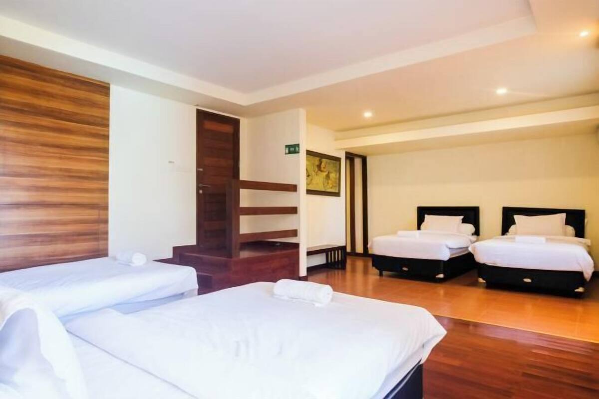 Ein Hotelzimmer mit zwei Einzelbetten, einer Wand mit Holzpaneelen, einer Treppe und einer Tür zu einem anderen Raum.