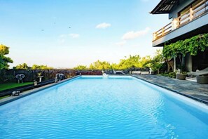A rectangular swimming pool with a clear blue surface, surrounded by a stone wall and potted plants. - The Lavana Villa Gajah Jimbaran (Bali)