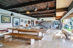 A spacious interior with a wooden bench, pendant lighting, and a staircase leading to an upper level. - The Lavana Villa Gajah Jimbaran (Bali)