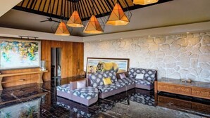 Un salon moderne avec un mur en pierre, un canapé d’angle et un meuble en bois.