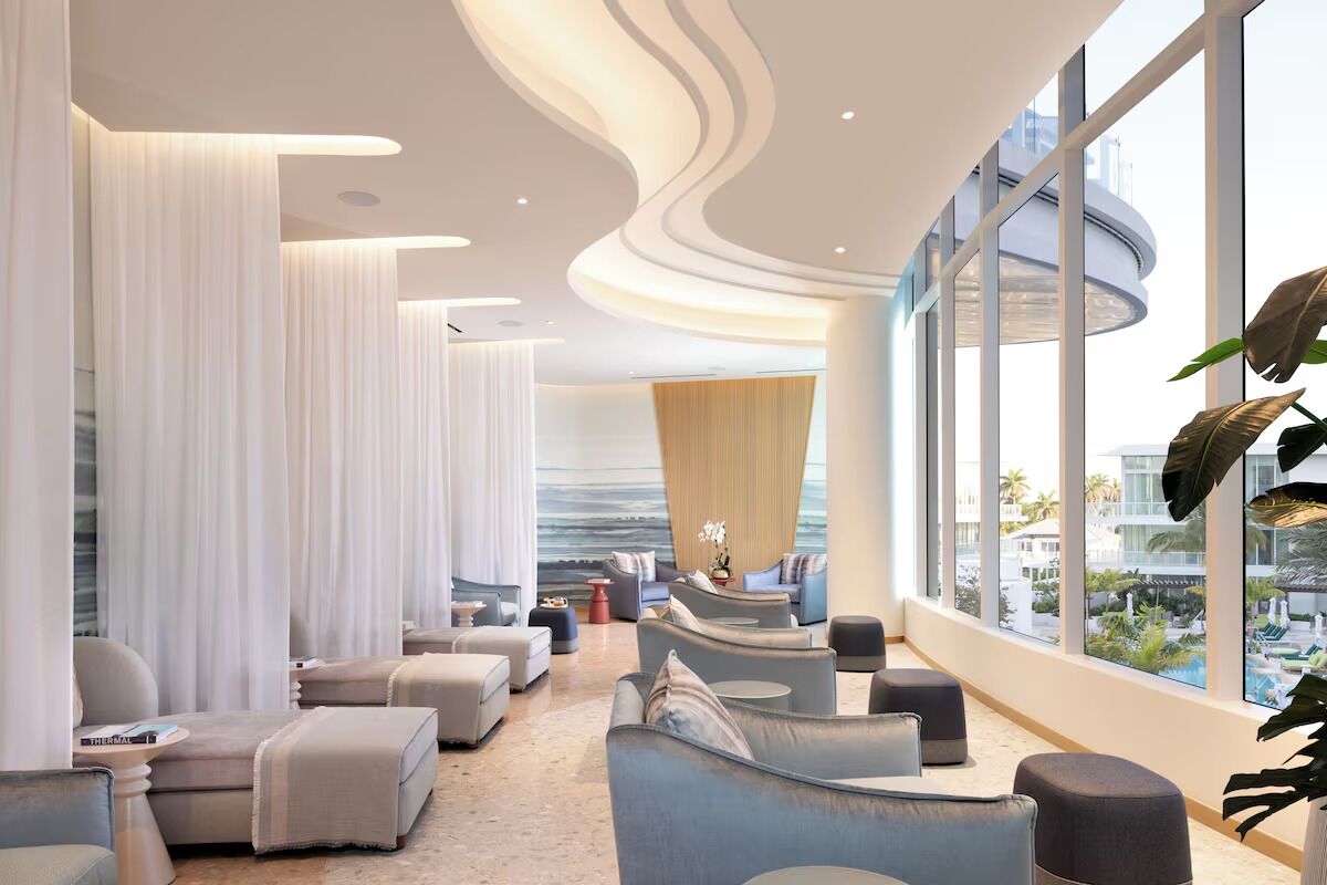 A modern lounge with seating, large windows, and a view of the outdoors.