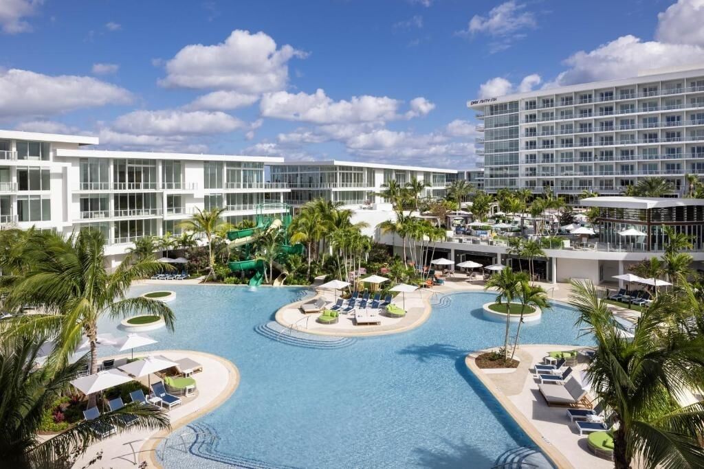 A resort with a large pool, palm trees, and modern buildings.