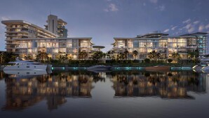 Een hotel aan het water met meerdere balkons, een zwembad en boten.